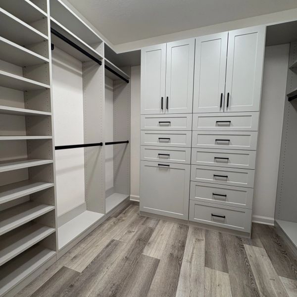 Modern empty walk-in closet with white shelves and drawers.