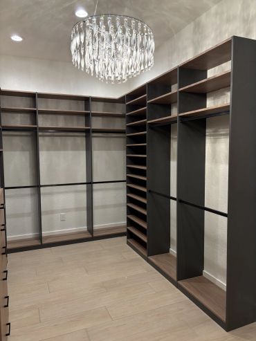 Empty walk-in closet with modern shelving and chandelier.