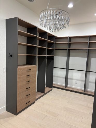 Empty walk-in closet with shelves and chandelier.
