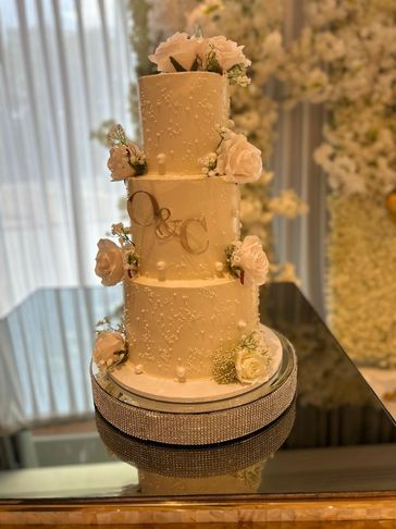 Elegant three-tiered wedding cake decorated with white flowers and pearls.