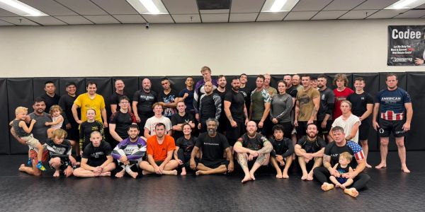 Large group of diverse people posing in a martial arts gym.