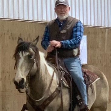 Man riding a horse indoors in casual attire.