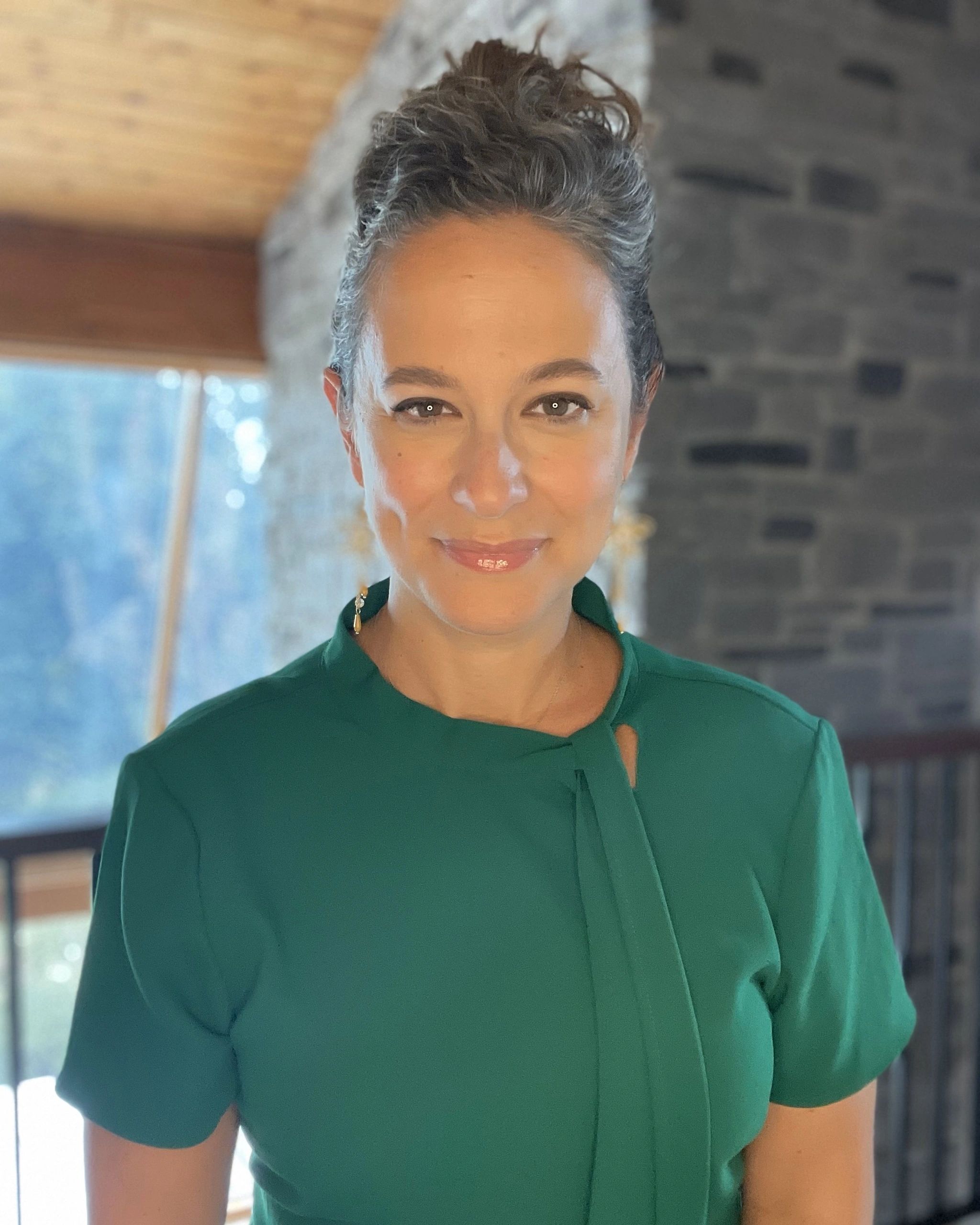 Woman with gray hair in a green top smiling.