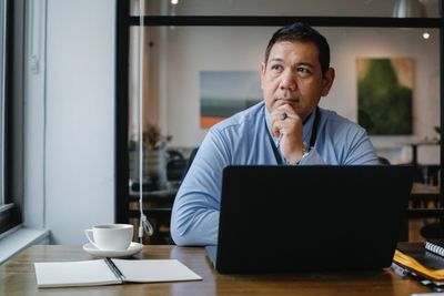 Thoughtful man working on laptop in a cozy cafe.
