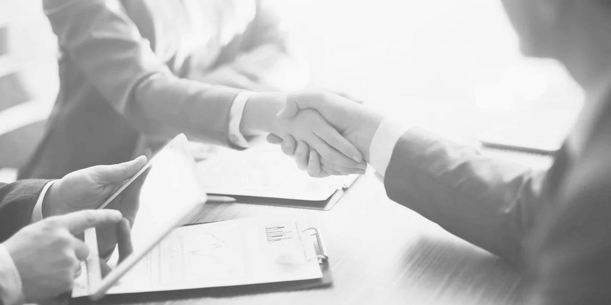 Two people shaking hands over a paper contract