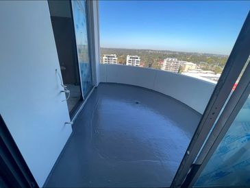 Empty balcony with a smooth gray floor and city view on a clear day.