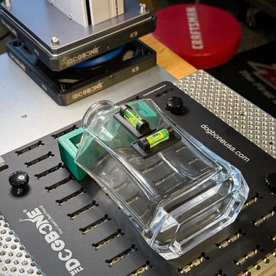 A clear glass bottle and two small batteries on a black docking station.