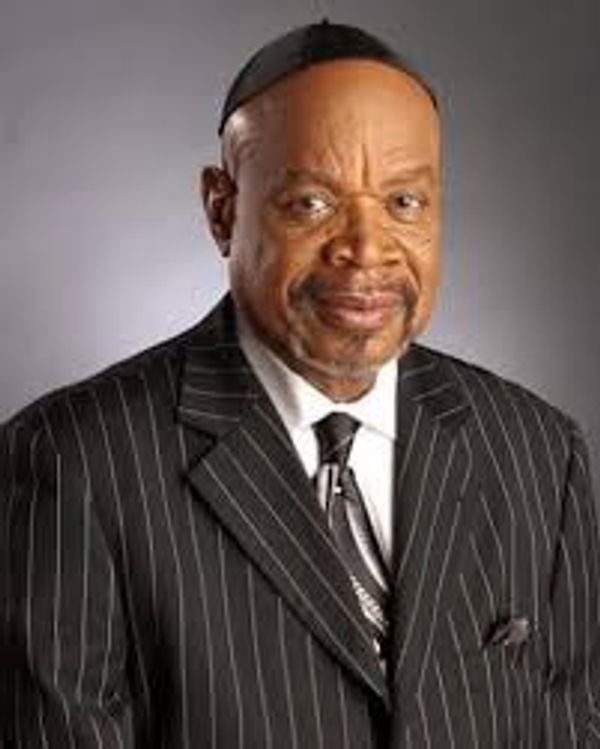 Elderly man in pinstripe suit and tie with a confident expression.