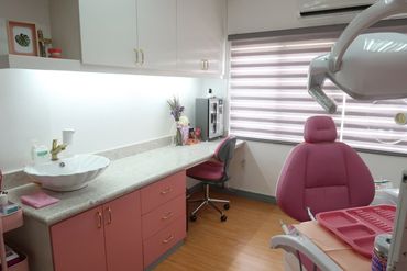 Modern dental office with pink-themed furniture and equipment.