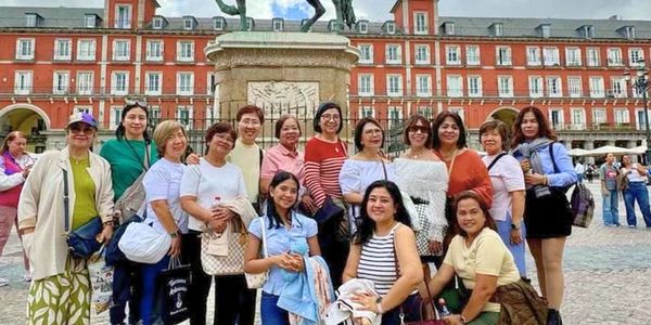 Group of tourists posing in front of a historic statue in Spain or Portugal.