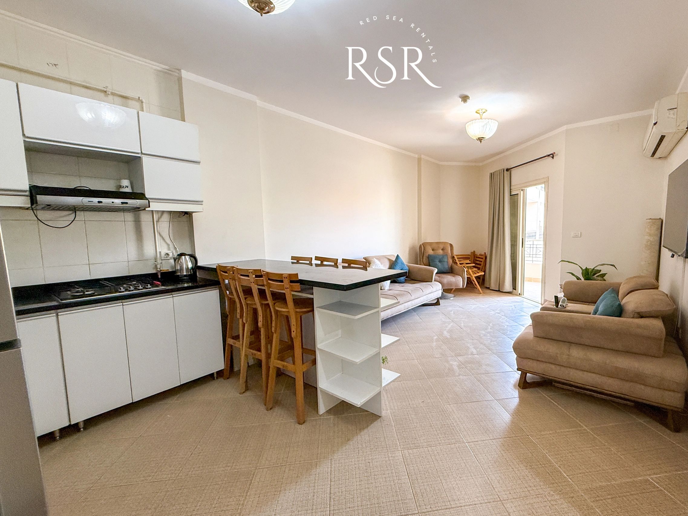 Bright and cozy open kitchen-living space with stools and comfortable seating.