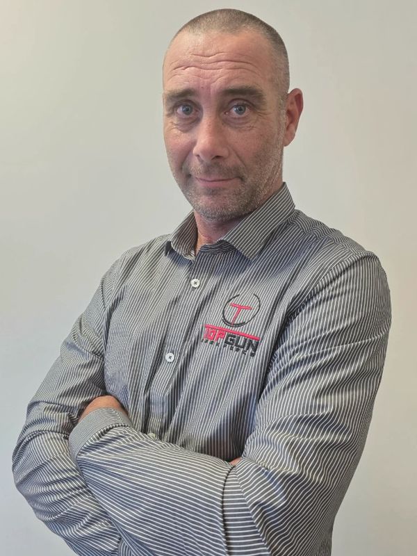 Man in a striped shirt with arms crossed, posing confidently.