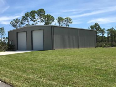 Large grey metal building on a green lawn.