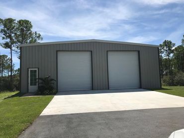 Small grey metal building with two white garage doors.