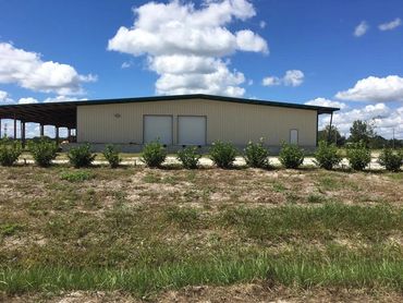 Long metal building exterior with low shrubs.