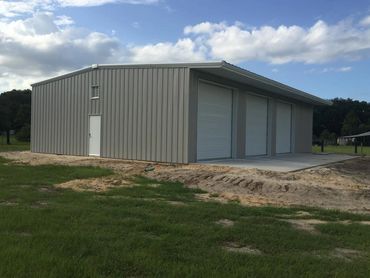 Newly finished grey metal building on a grass lot.