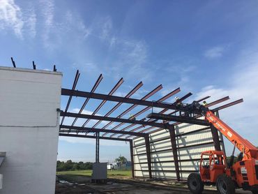 Metal building structure with roof frame against sky.