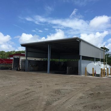 Dark grey metal building under construction with dirt.