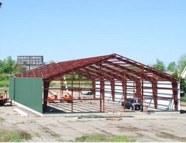 Red steel frame structure under construction outdoors.