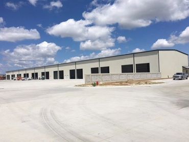 View of long row of similar grey metal buildings.