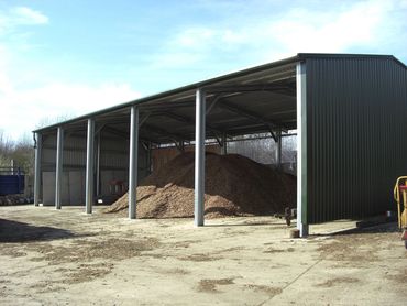 Open-sided metal shed structure storing materials.