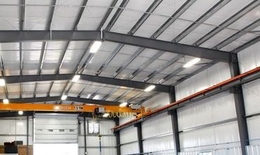Bright interior of metal building with yellow crane.