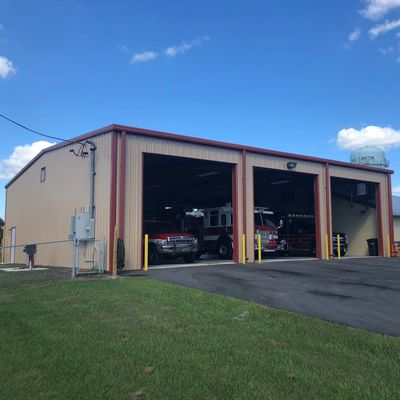 Metal fire station building with three bays and fire trucks.