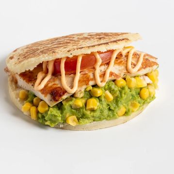 Grilled fish sandwich with guacamole, corn, and sauce.