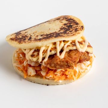 Arepa with grilled cheese, meat, and sauce.
