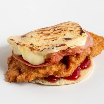 Fried chicken sandwich with bacon, melted cheese, and sauce.