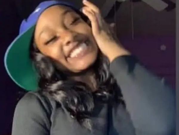 Smiling young woman wearing a backward blue cap and black top.