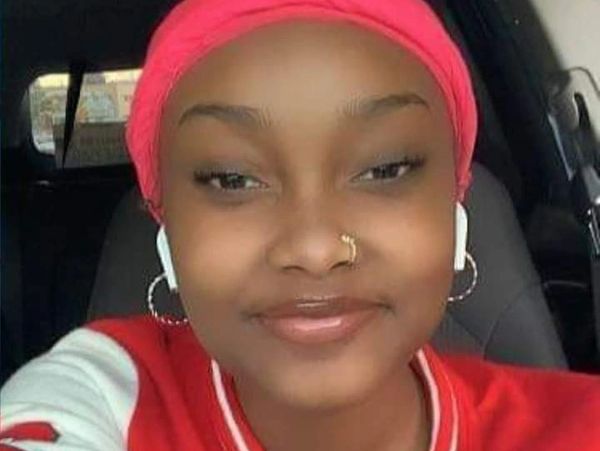A smiling young woman wearing a red headscarf and AirPods.