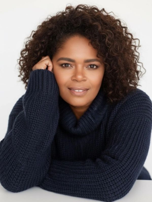 Woman with curly hair in a navy sweater smiling.
