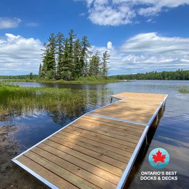 Wooden dock extending into a calm lake with a small island and trees in the background.
