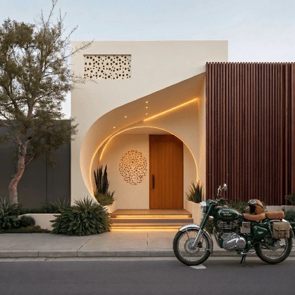 Modern house entrance with warm lighting and a vintage green motorcycle parked outside.
