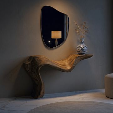 Organic wooden console with a decorative vase and an irregular mirror in a minimalistic room.