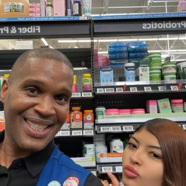 Two people smiling and posing for a selfie in a store aisle.