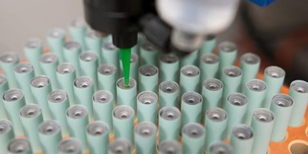 Close-up of a machine assembling cylindrical batteries.
