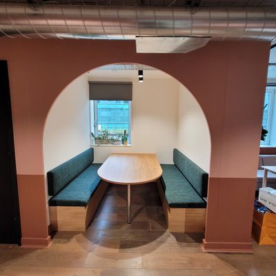 Cozy seating nook with green cushioned benches and wooden table under an archway.