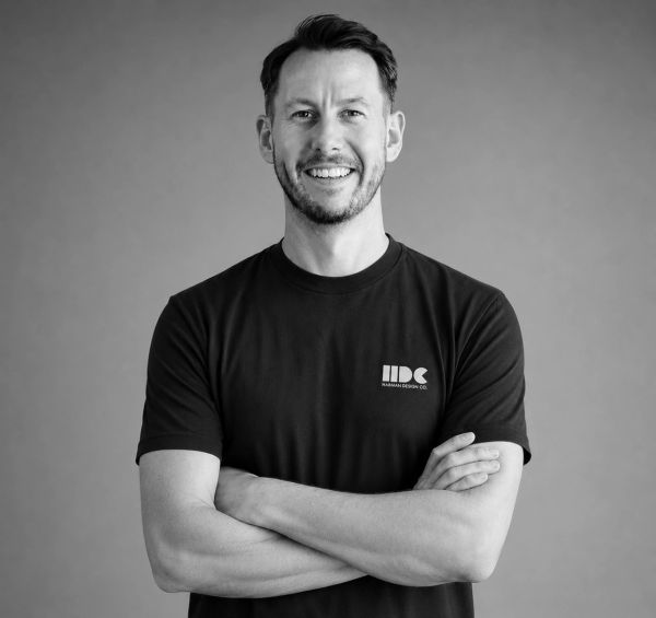Smiling man with crossed arms wearing a black t-shirt.