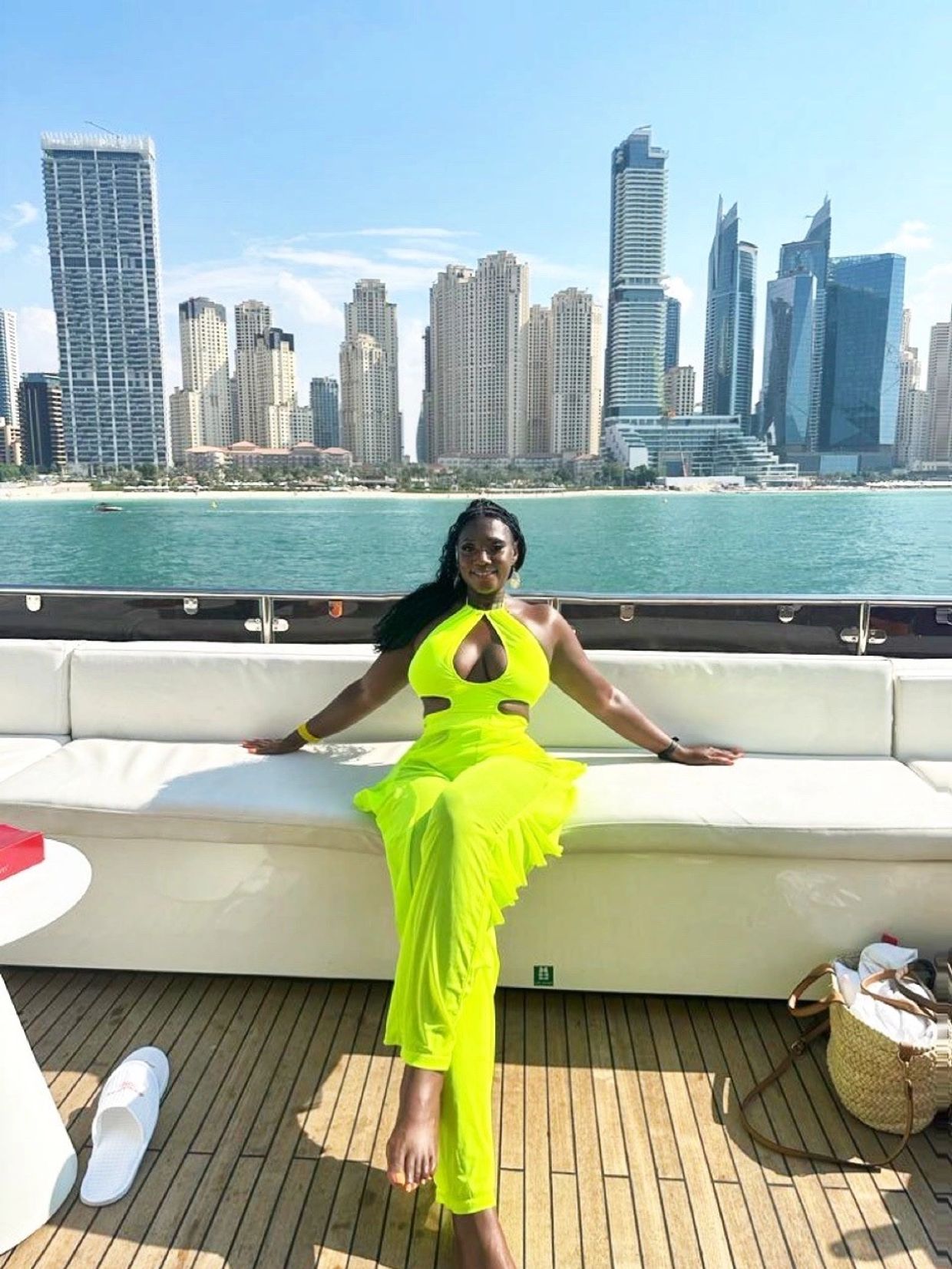 Woman in a bright yellow dress relaxing on a boat with city skyline background.