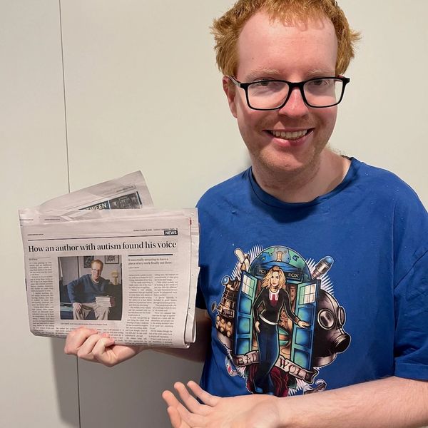 Liam holding a copy of the Canberra Times showing the article about him.