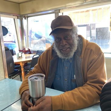 Man with hat and beard sitting at the counter