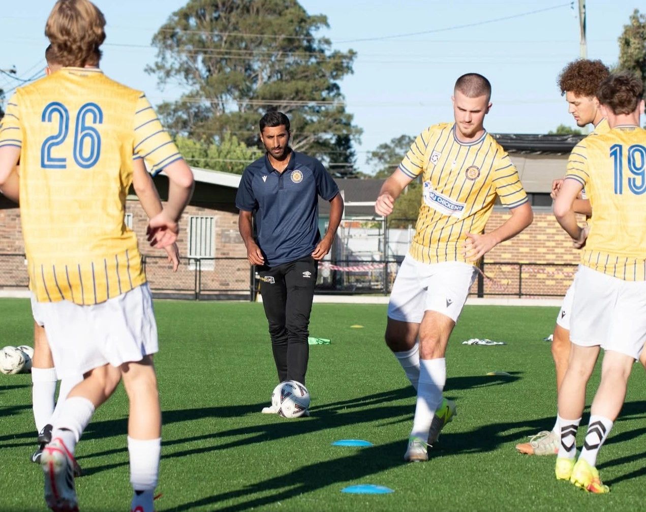 Soccer coach training players on a sunny field.