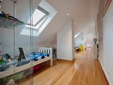 Bright attic hallway with skylights and children’s beds.