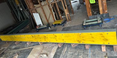 Yellow construction beam resting on bricks inside a partially demolished building.
