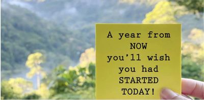 A motivational note held up against a scenic, blurred natural background.