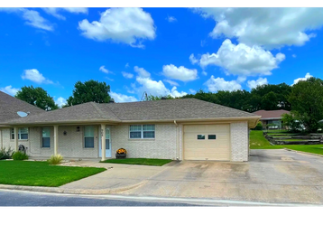 Single-story house with a garage and bright blue sky.