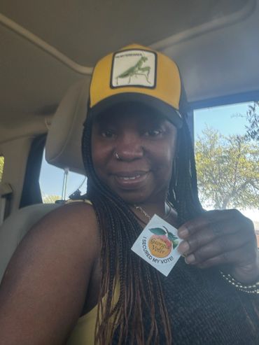Woman smiling inside car holding an 'I Secured My Vote' sticker.