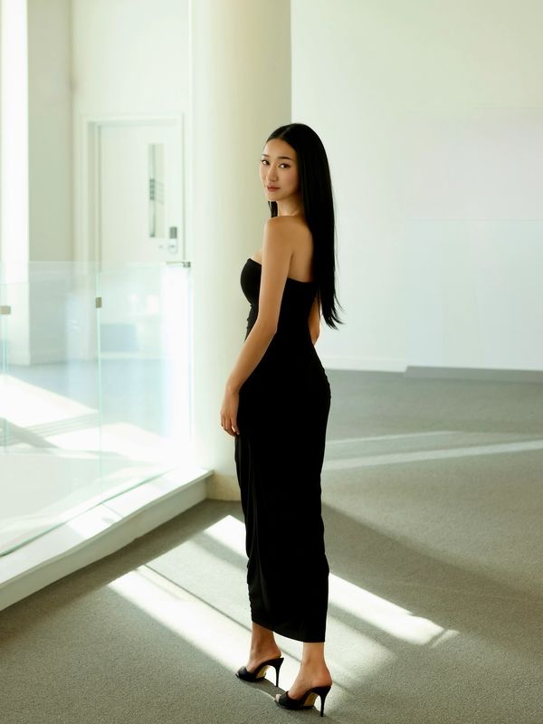 Woman in elegant black dress posing indoors.